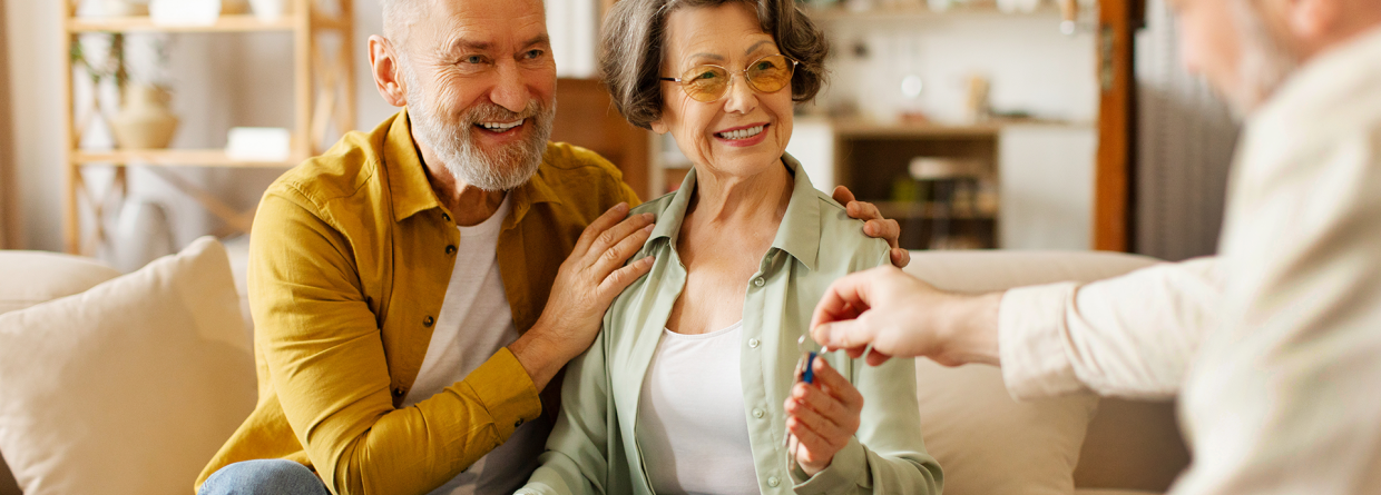 Makelaar geeft de sleutels van een woning aan een senior koppel