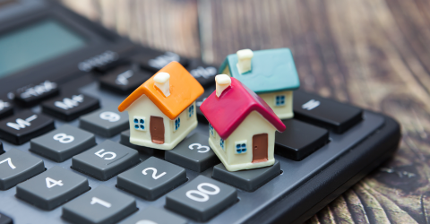 Hypotheek; drie kleine huisjes staan op een rekenmachine